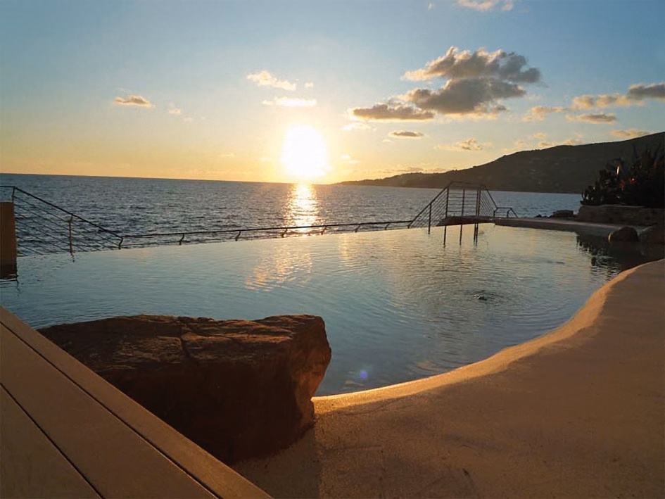 The sun setting over the sea, seen from the edge of a natural pool